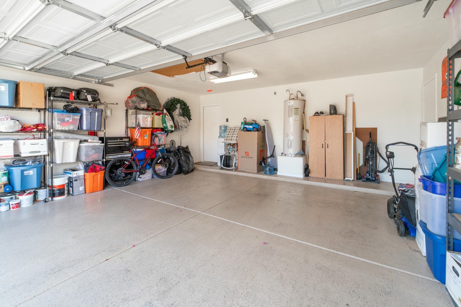 A garage filled with lots of boxes , tools , and a water heater.