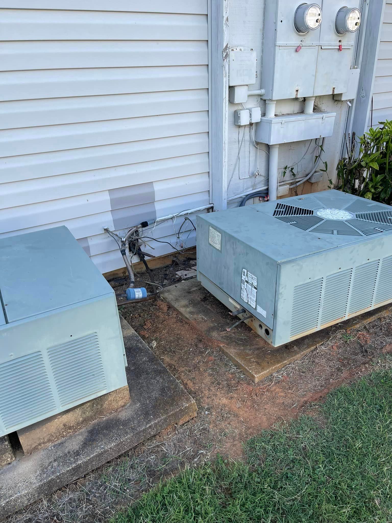 Two air conditioners are sitting on the side of a house.