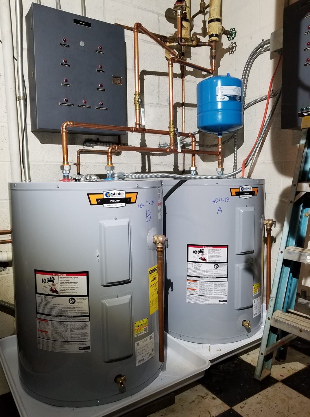 Two water heaters are sitting next to each other in a room.