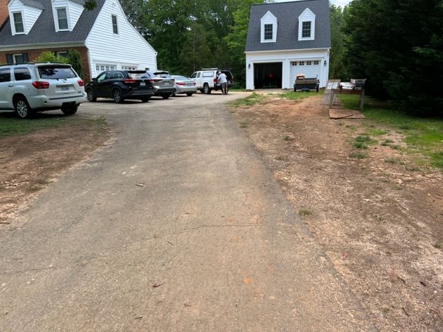 A row of cars are parked on the side of a dirt road