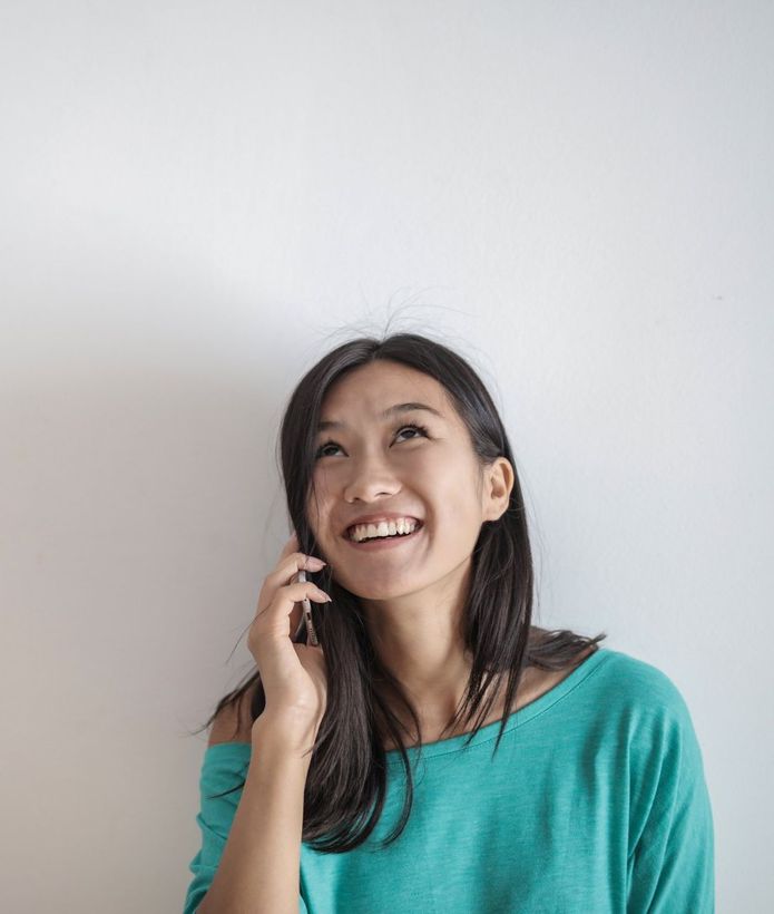 A woman is smiling while talking on a cell phone.