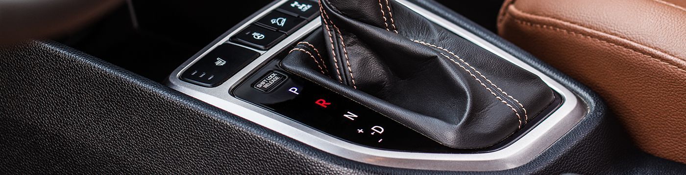 Car gear shift console with silver trim and black leather.