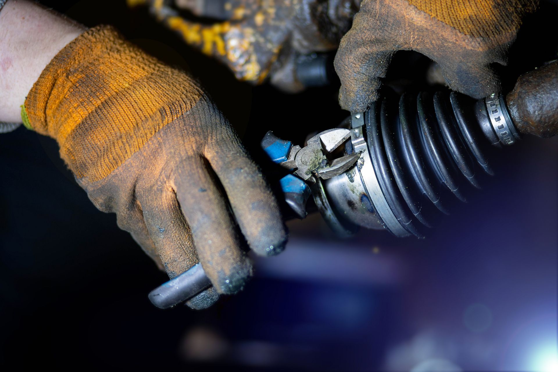 A person wearing gloves is working on a steering shaft.