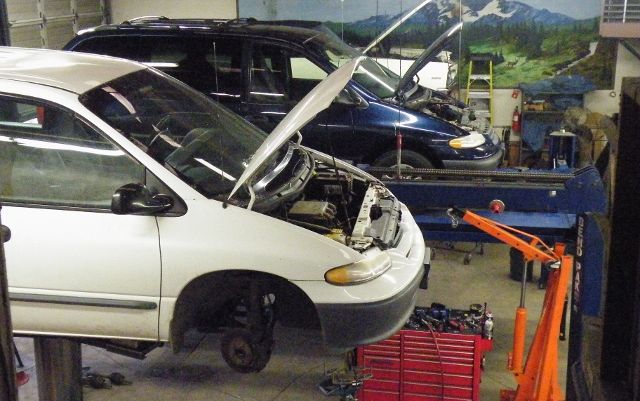 A white van is sitting on a lift with its hood open