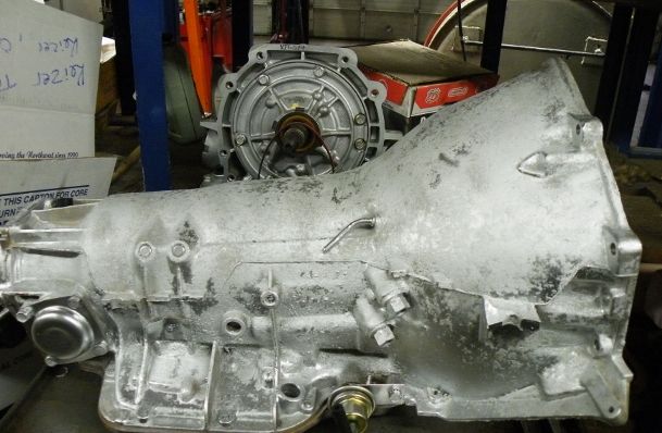 A gearbox is sitting on a shelf in a garage.