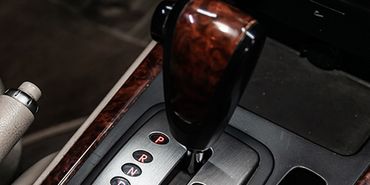 A close up of a wooden gear shifter in a car.