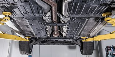 The underside of a car on a lift in a garage.