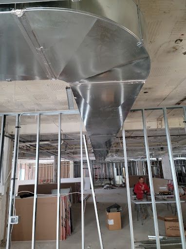 A large stainless steel pipe is hanging from the ceiling of a building under construction.