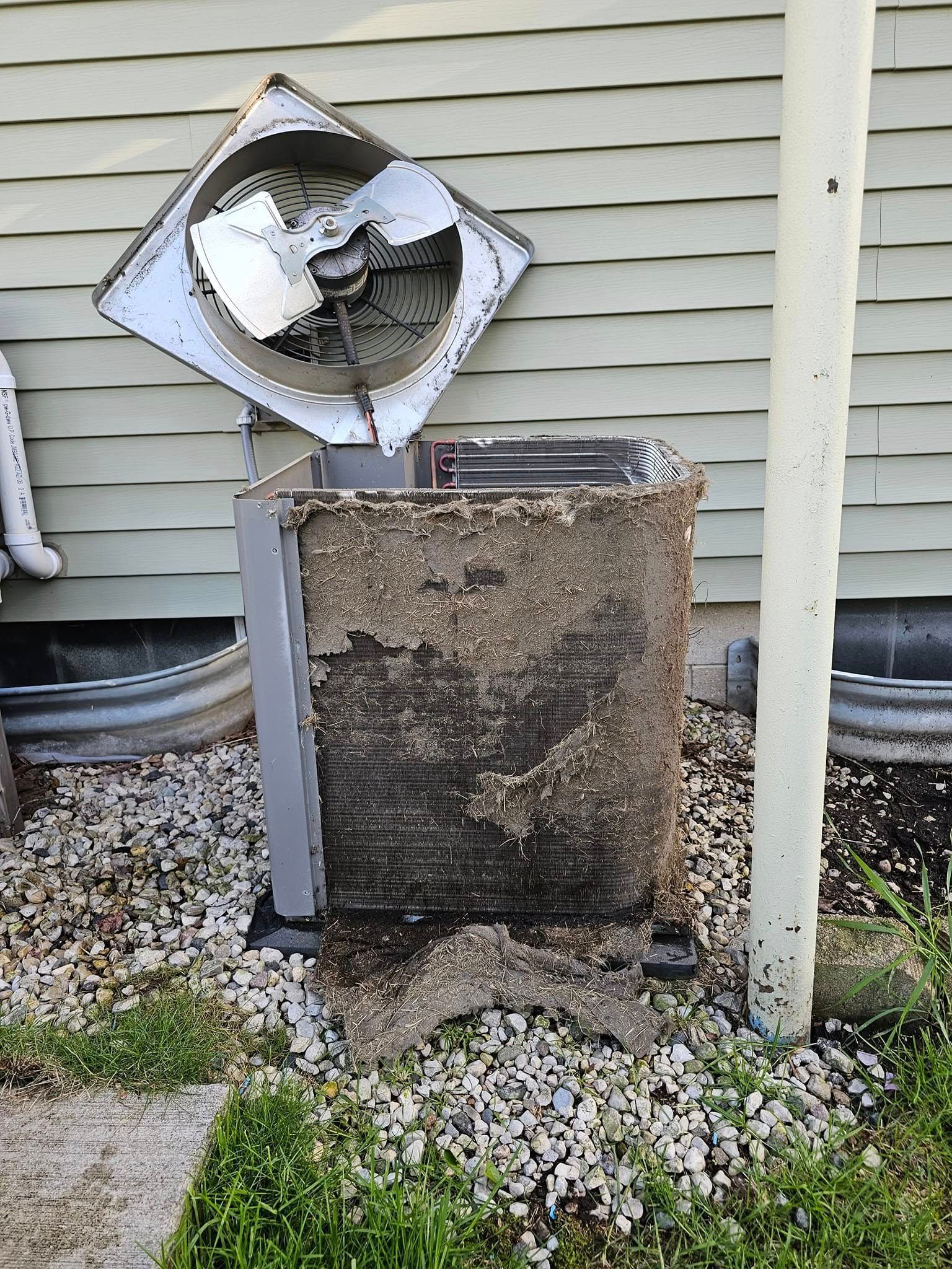 A broken air conditioner is sitting on the side of a house.