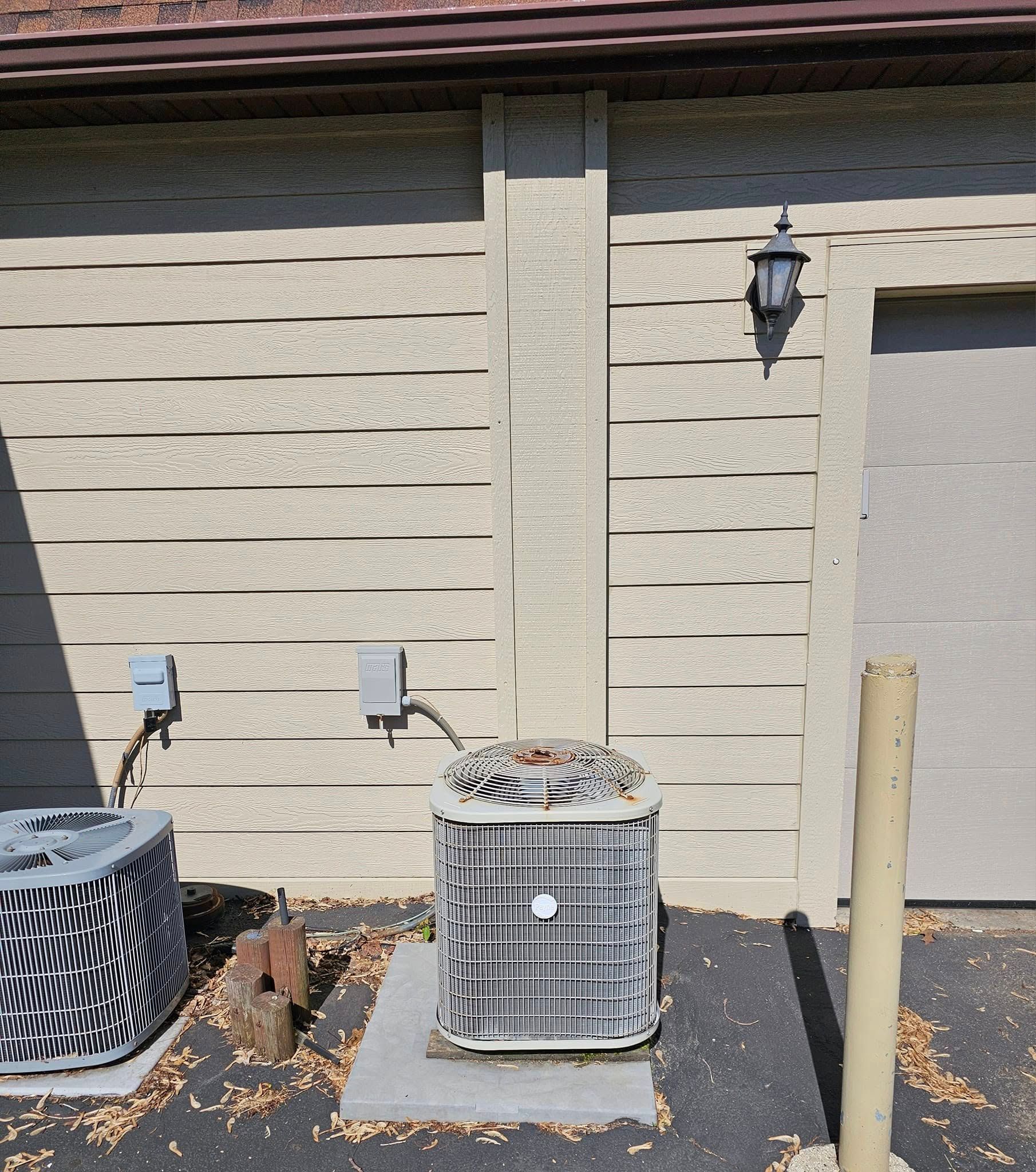 A black and white air conditioner sits outside of a garage