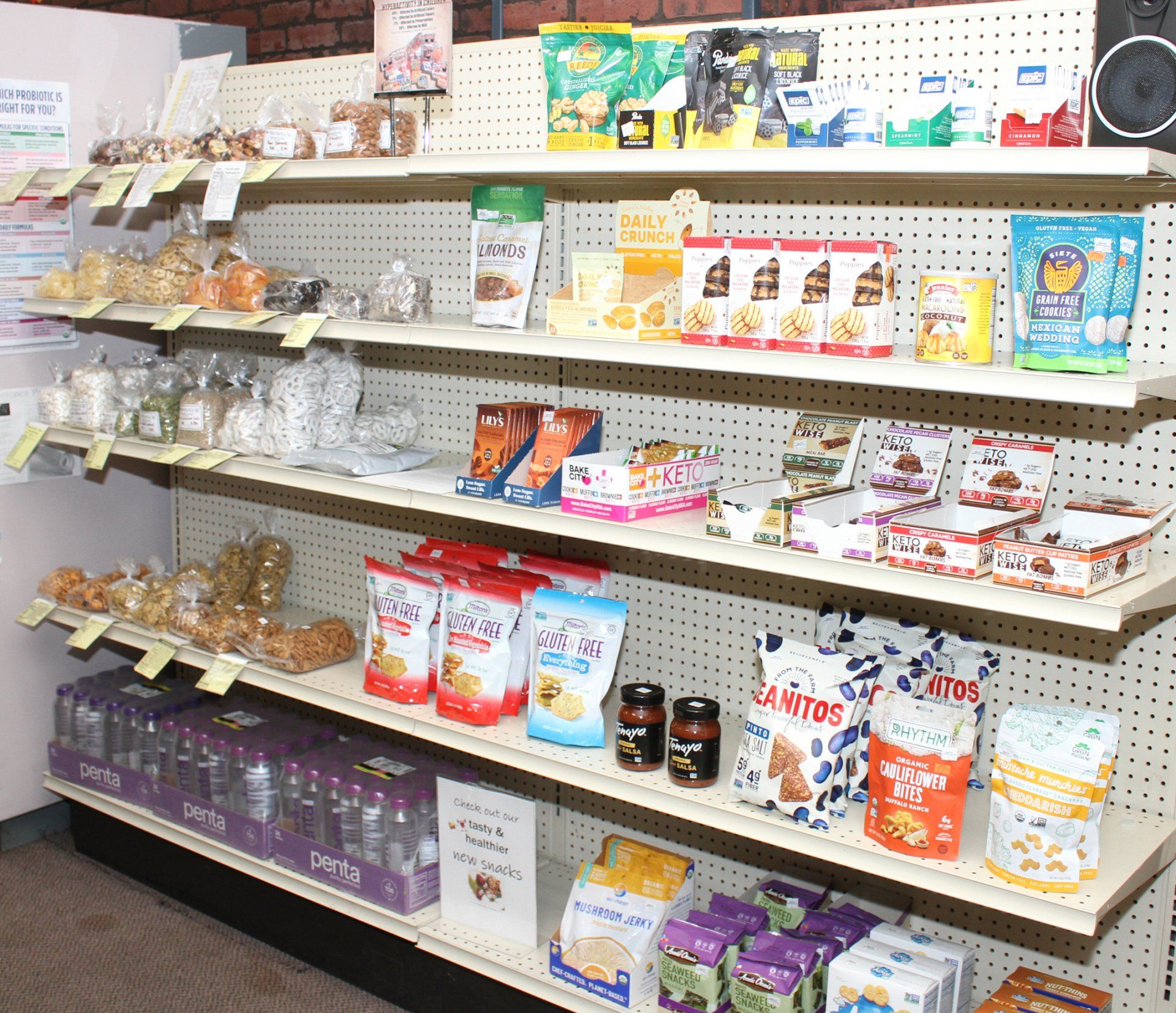 Retail shelving unit displaying various packaged snacks, jars, and small food items in a tidy store setting.