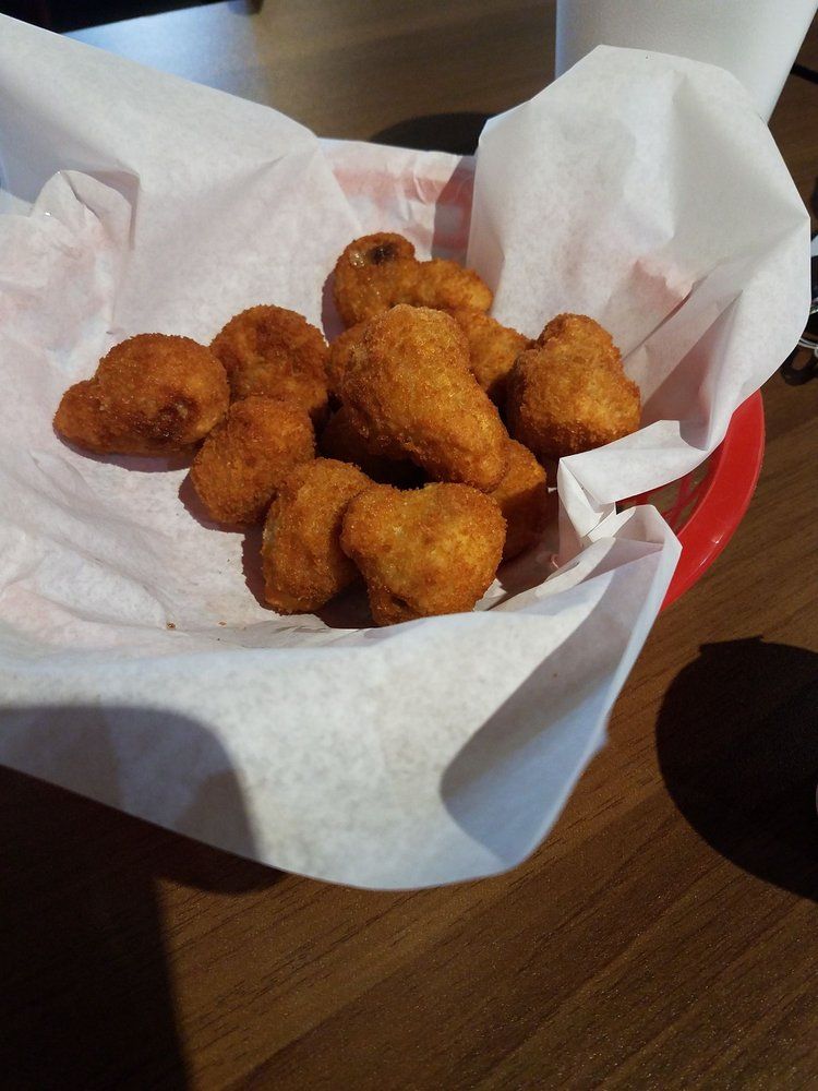 Basket of fried mushroom pieces, served in a red basket lined with white paper.