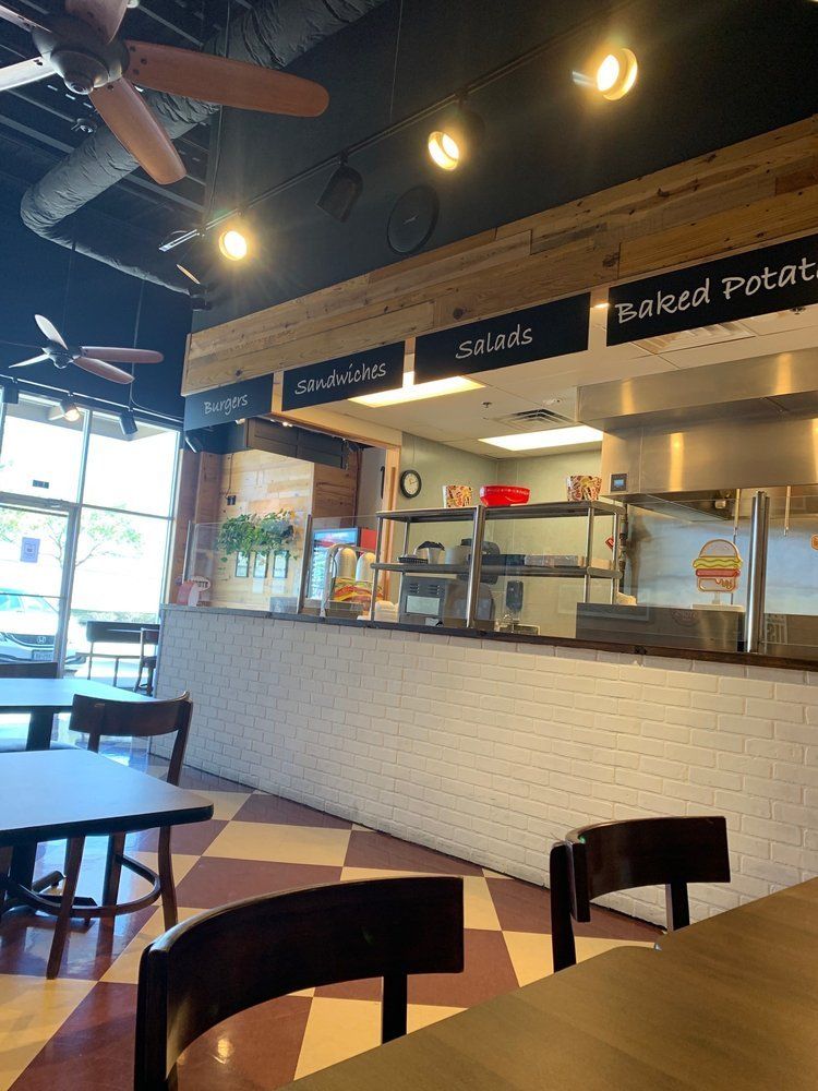 Interior of a restaurant with ordering counter, checkerboard floor, tables, and menu signs.