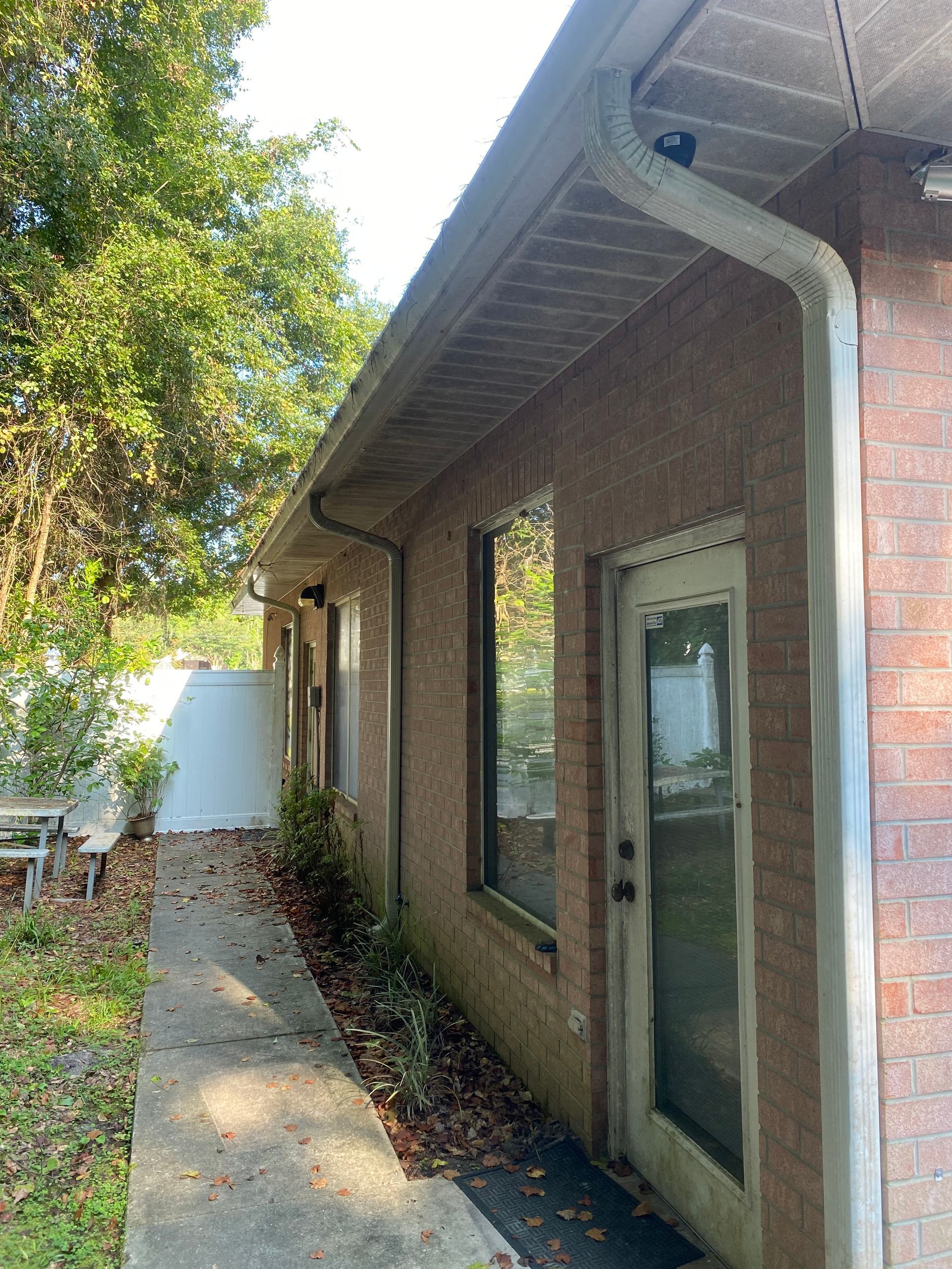 A brick house with a door and a gutter on the side of it