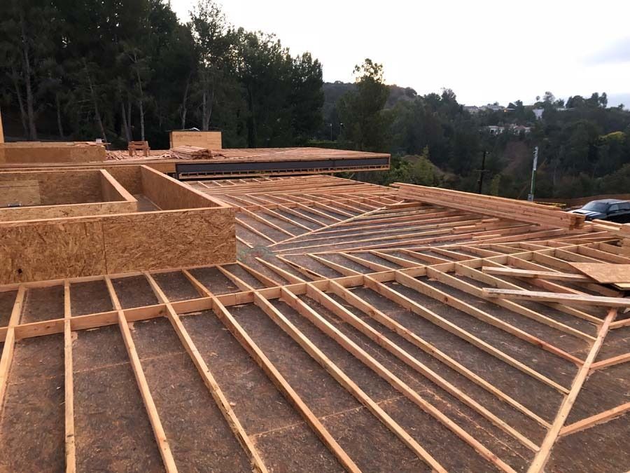 Construction site with wooden framing and building materials, outdoors, daytime.