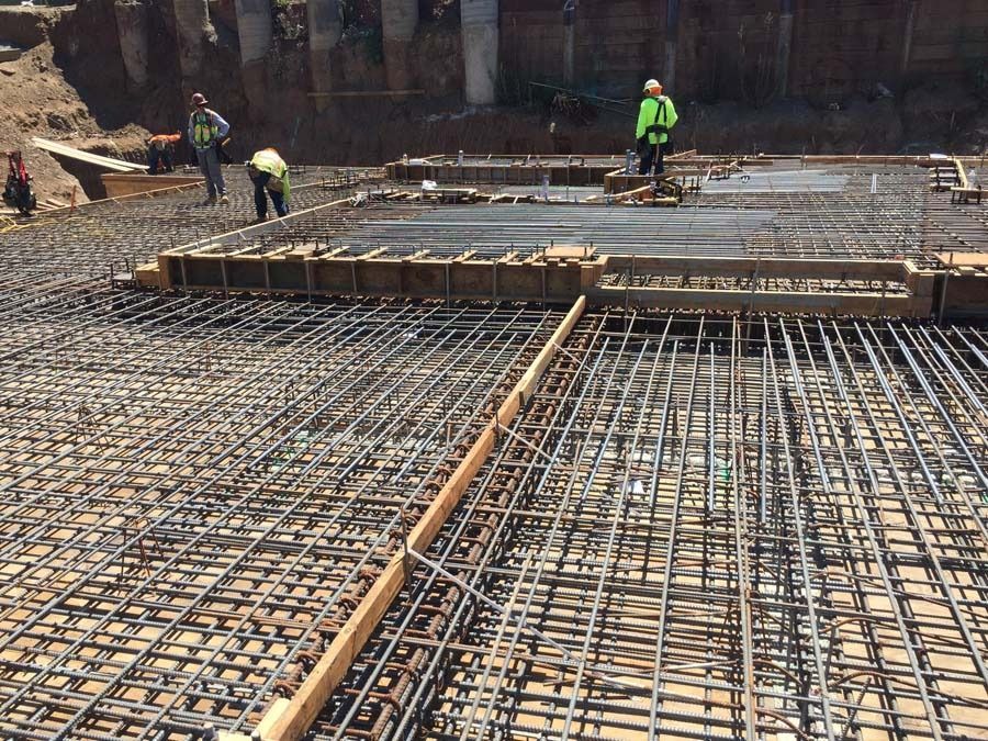 Construction workers on a site, preparing rebar for concrete foundation.