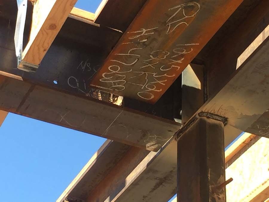Steel beams joined with welds, forming a structural support, construction site.