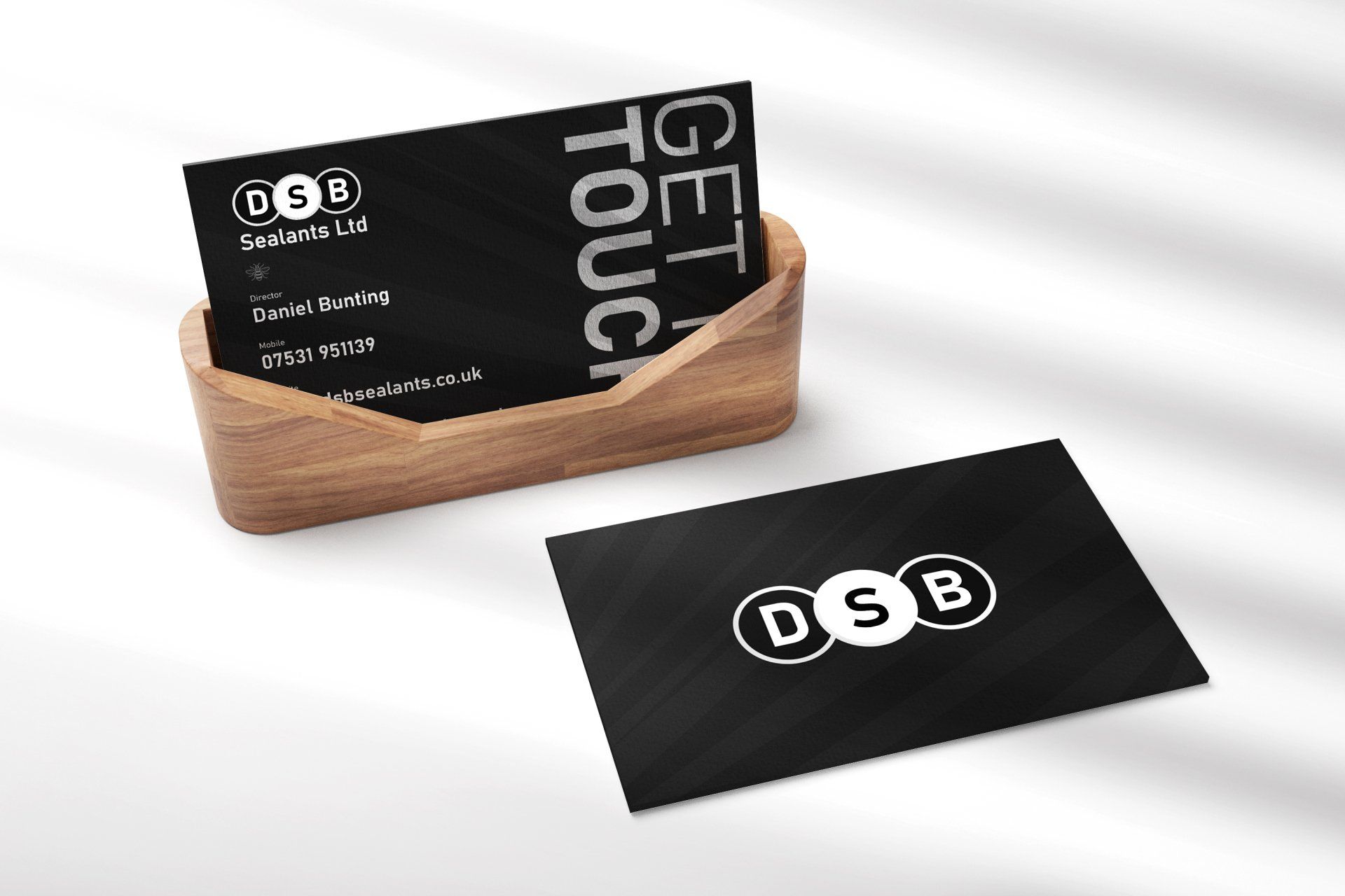 Business cards in a wooden holder. Black cards with the DSB logo and contact info.
