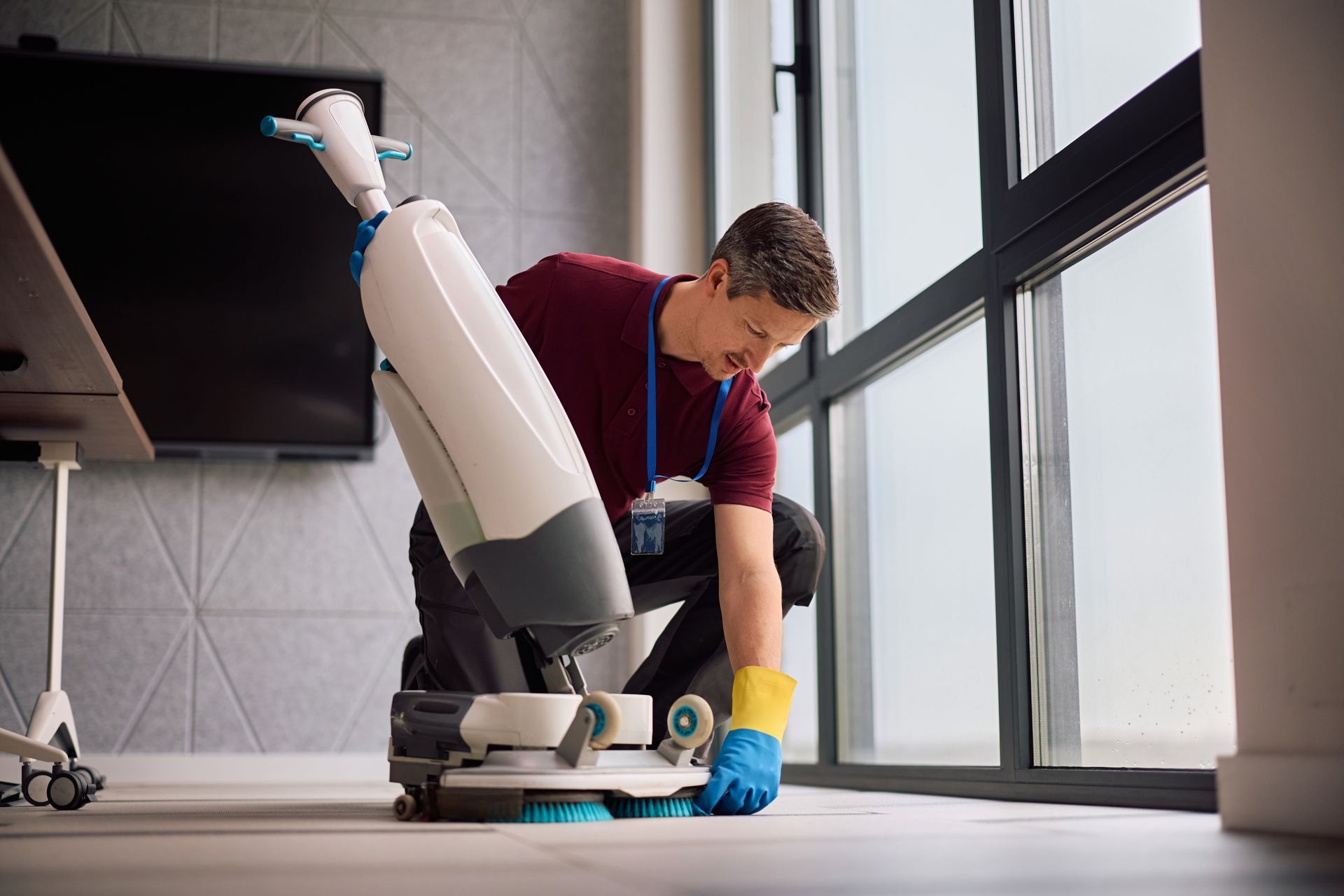 Person cleaning a floor with a robotic vacuum in a bright room