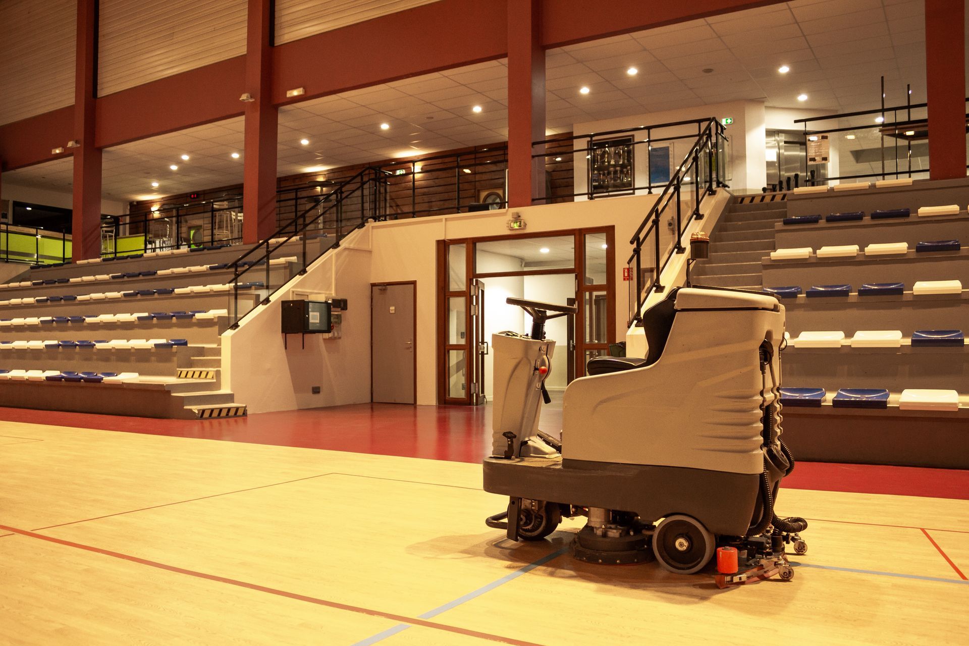 Cleaning cart in a gymnasium with bleachers and polished floor