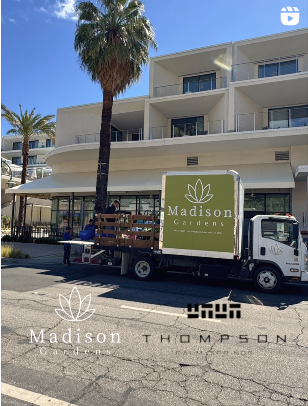 A delivery truck from Madison Gardens parked outside a modern building with a palm tree in Palm Springs.