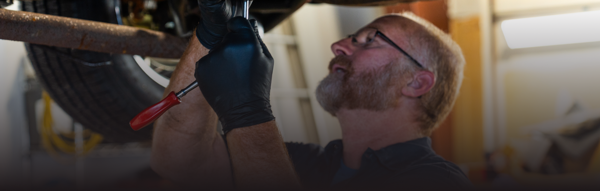 Technician working under vehicle in Olathe, KS | Smith Specialty Automotive
