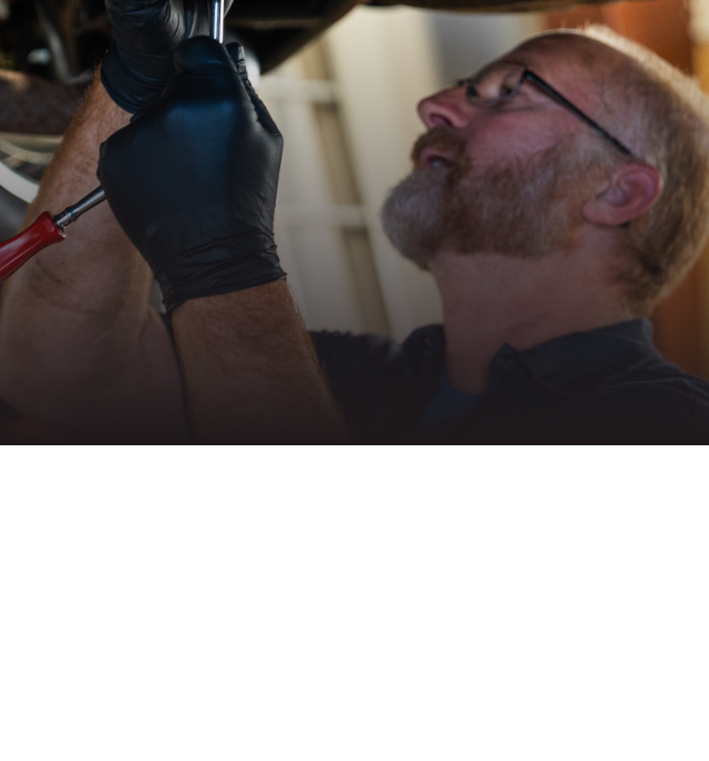 Technician working under vehicle in Olathe, KS | Smith Specialty Automotive