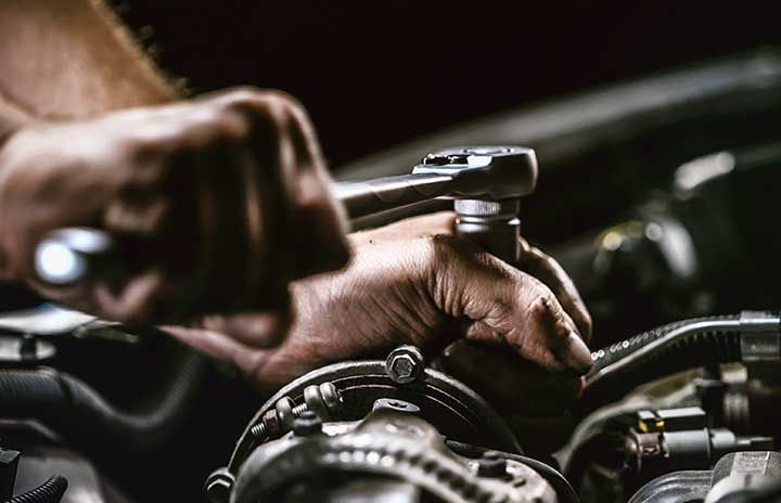Auto mechanic working on car engine in mechanics
