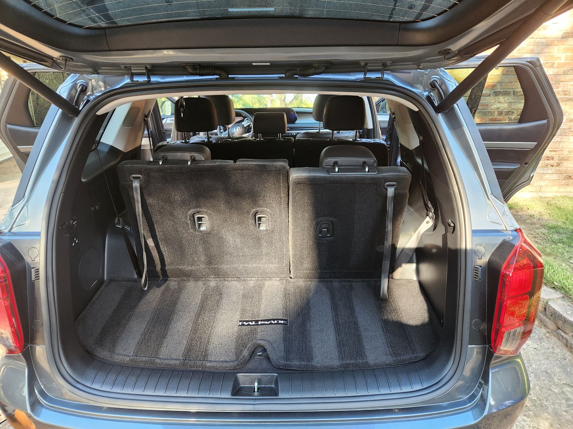 Open trunk of a grey SUV, revealing clean cargo space and back seats.