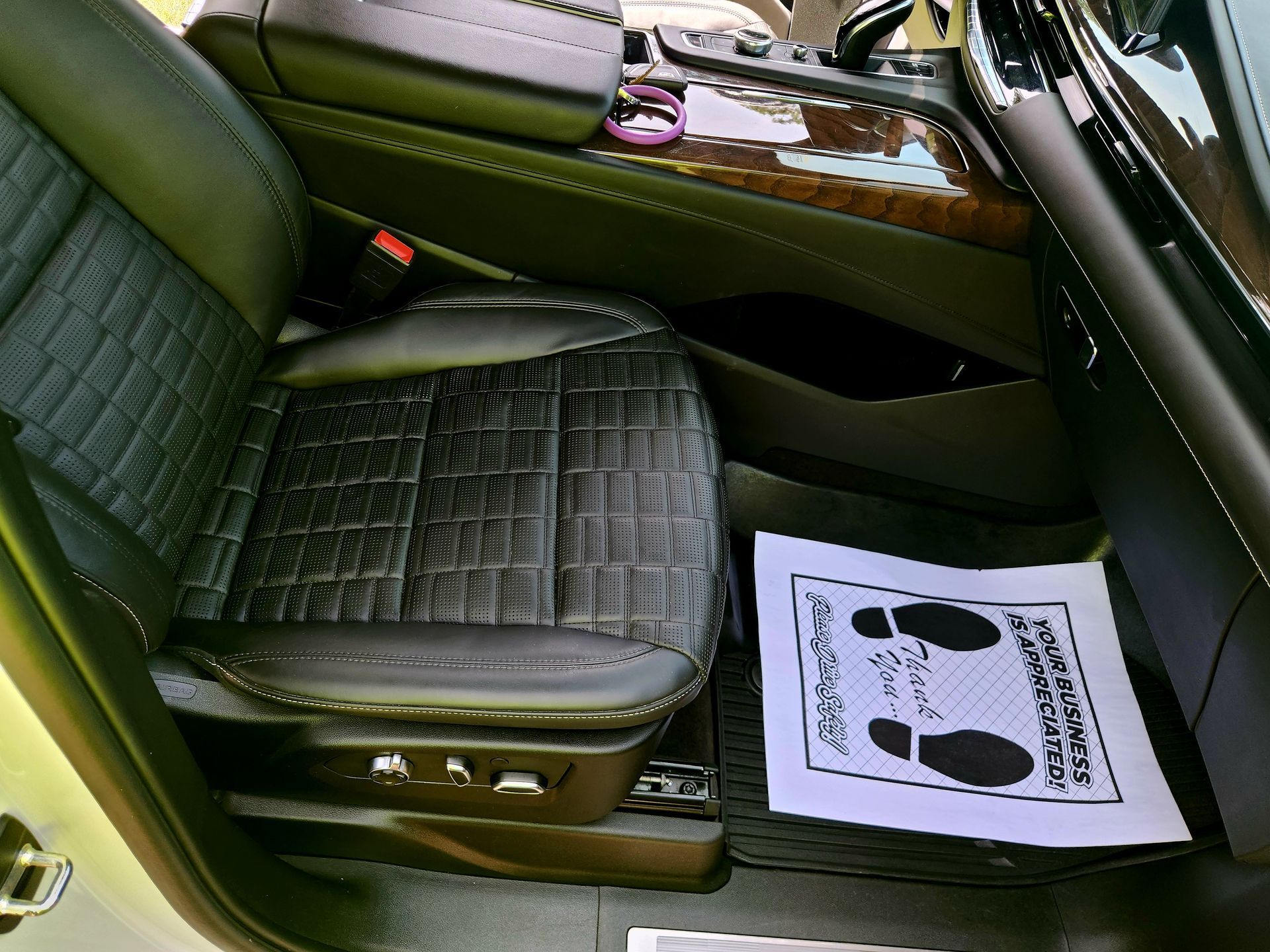 Car interior with black seat, center console, and a floor mat showing footprint directions