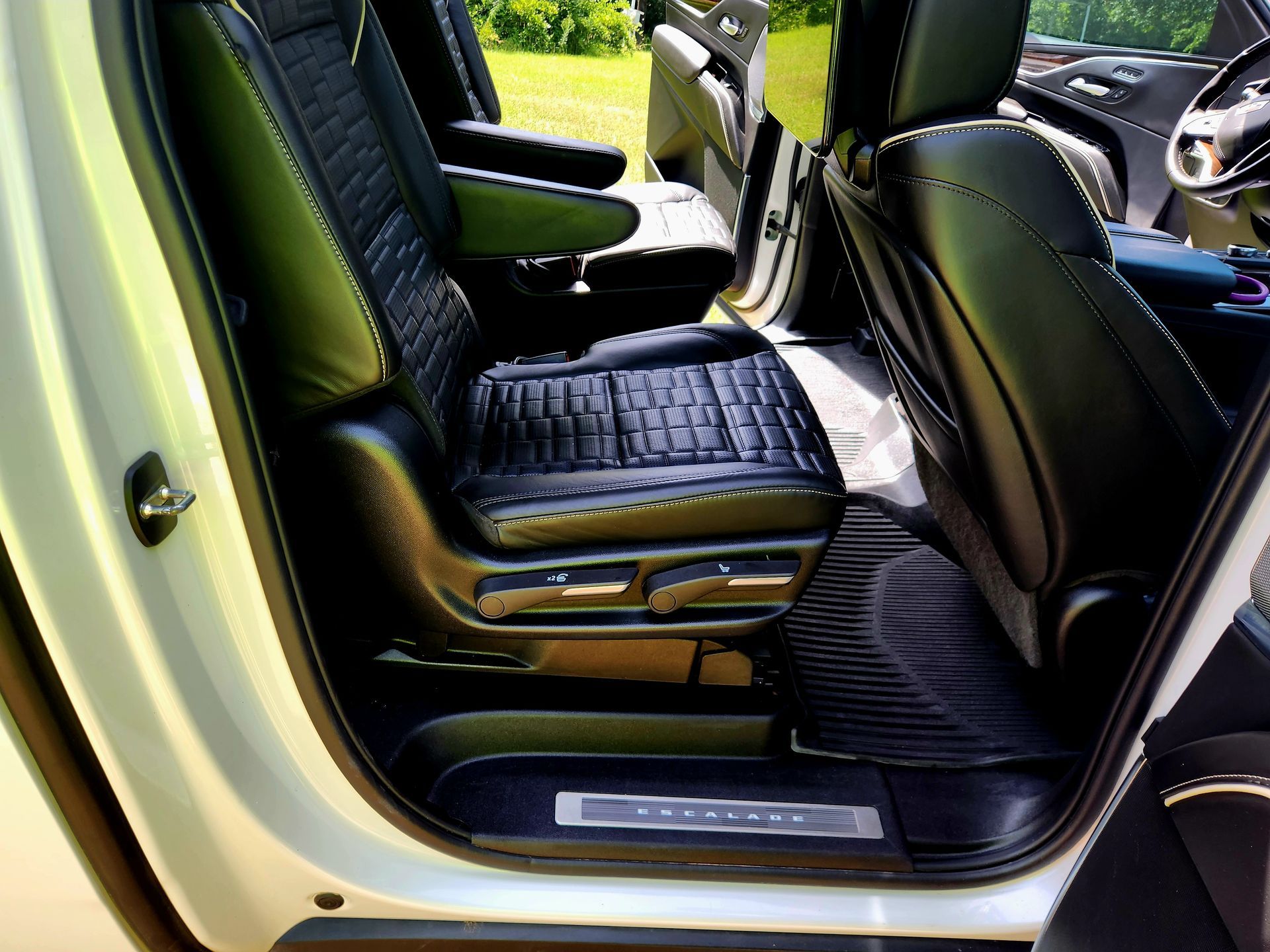 Open car door showing black leather seats and dashboard inside a green vehicle