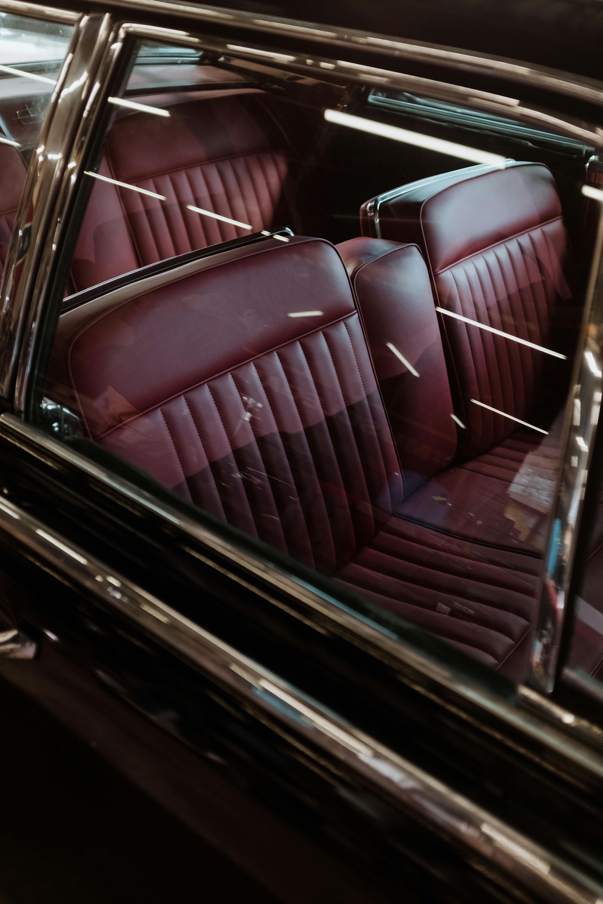 Dark maroon leather car seats seen through a tinted window.