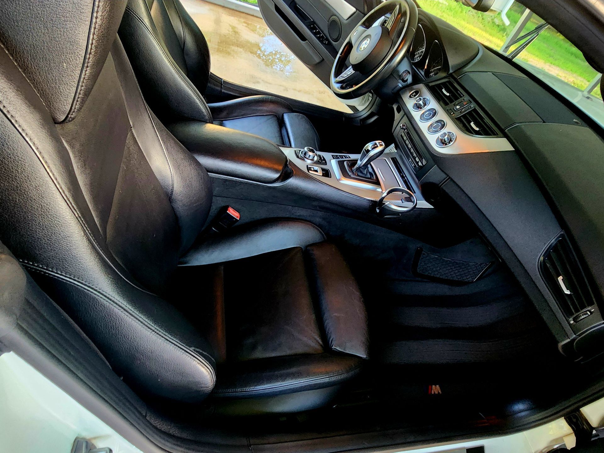 Black leather car front seat and center console with gear shifter and cup holders in a luxury interior