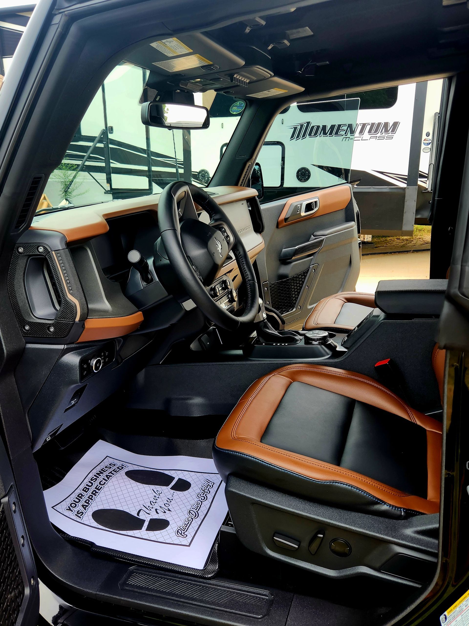 Custom black-and-brown vehicle interior with steering wheel and front passenger seat, viewed from the open door