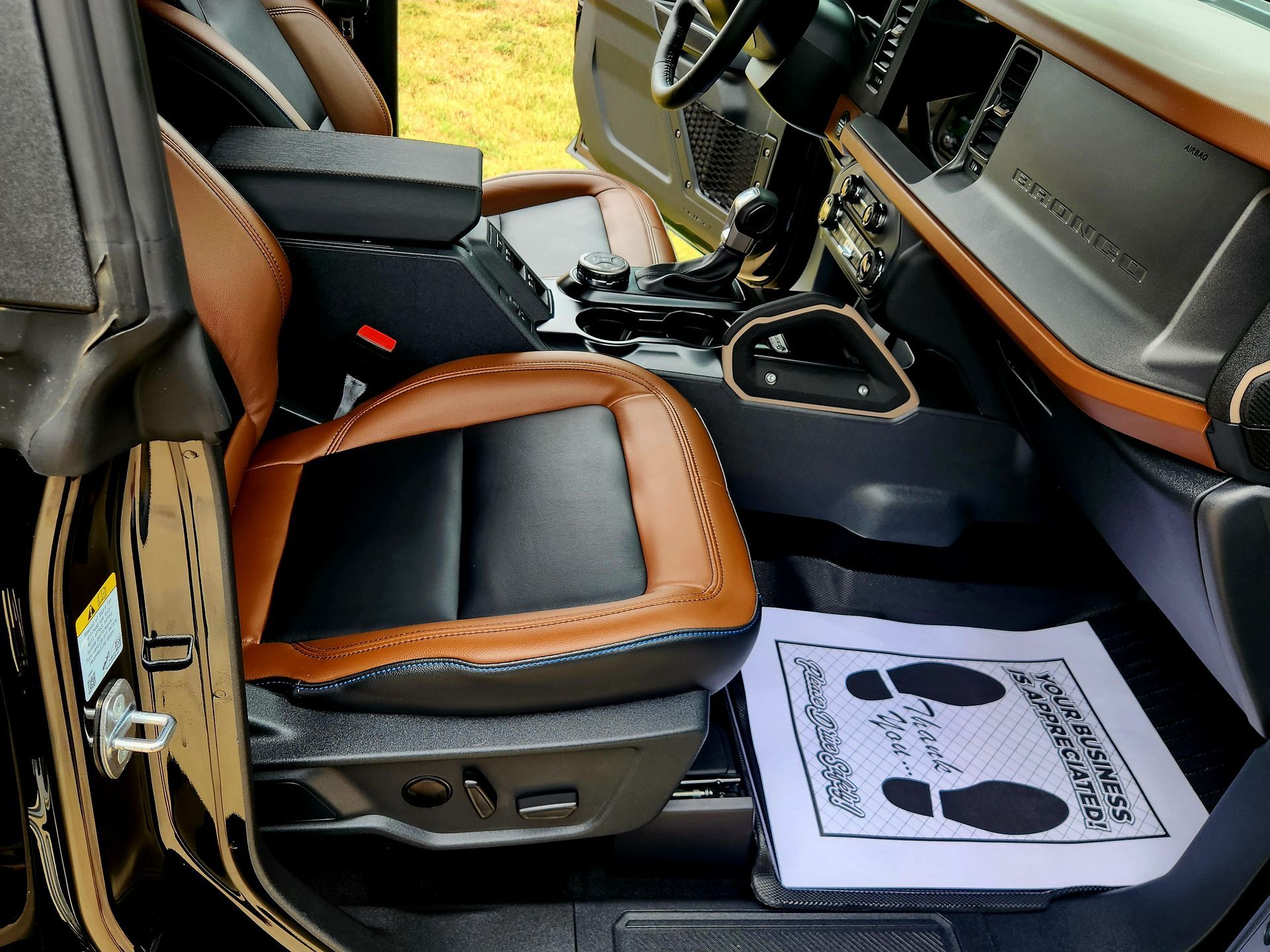 Black-and-tan car interior with front seats and a floor mat on the passenger side.