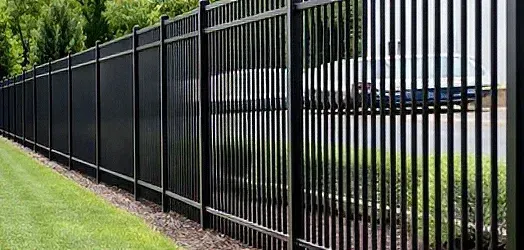 Black metal fence along a green roadside beside a paved street