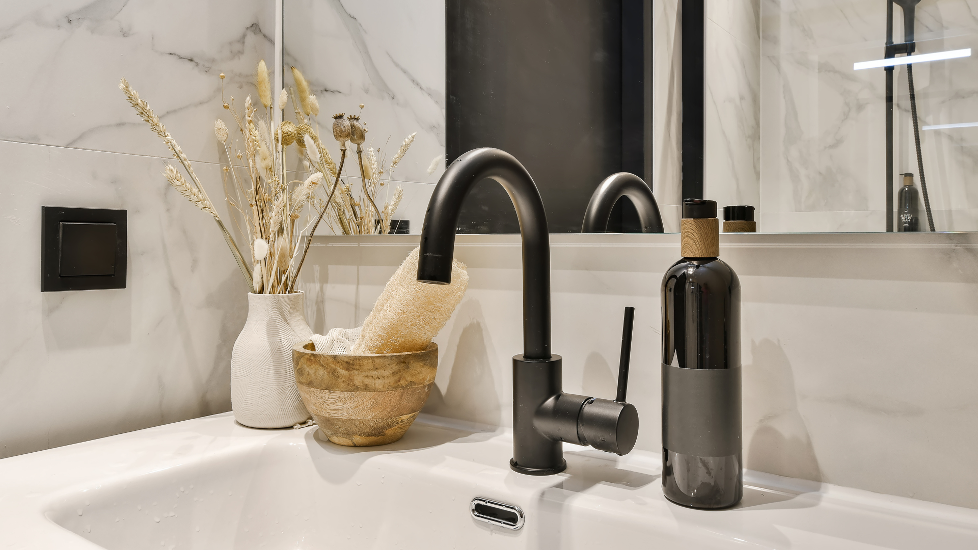 A bathroom sink with a black faucet and a bottle of soap.