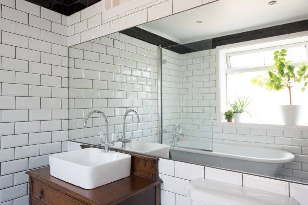 Bathroom with white subway tiles, a large mirror, a bathtub, and a sink on a wooden cabinet.