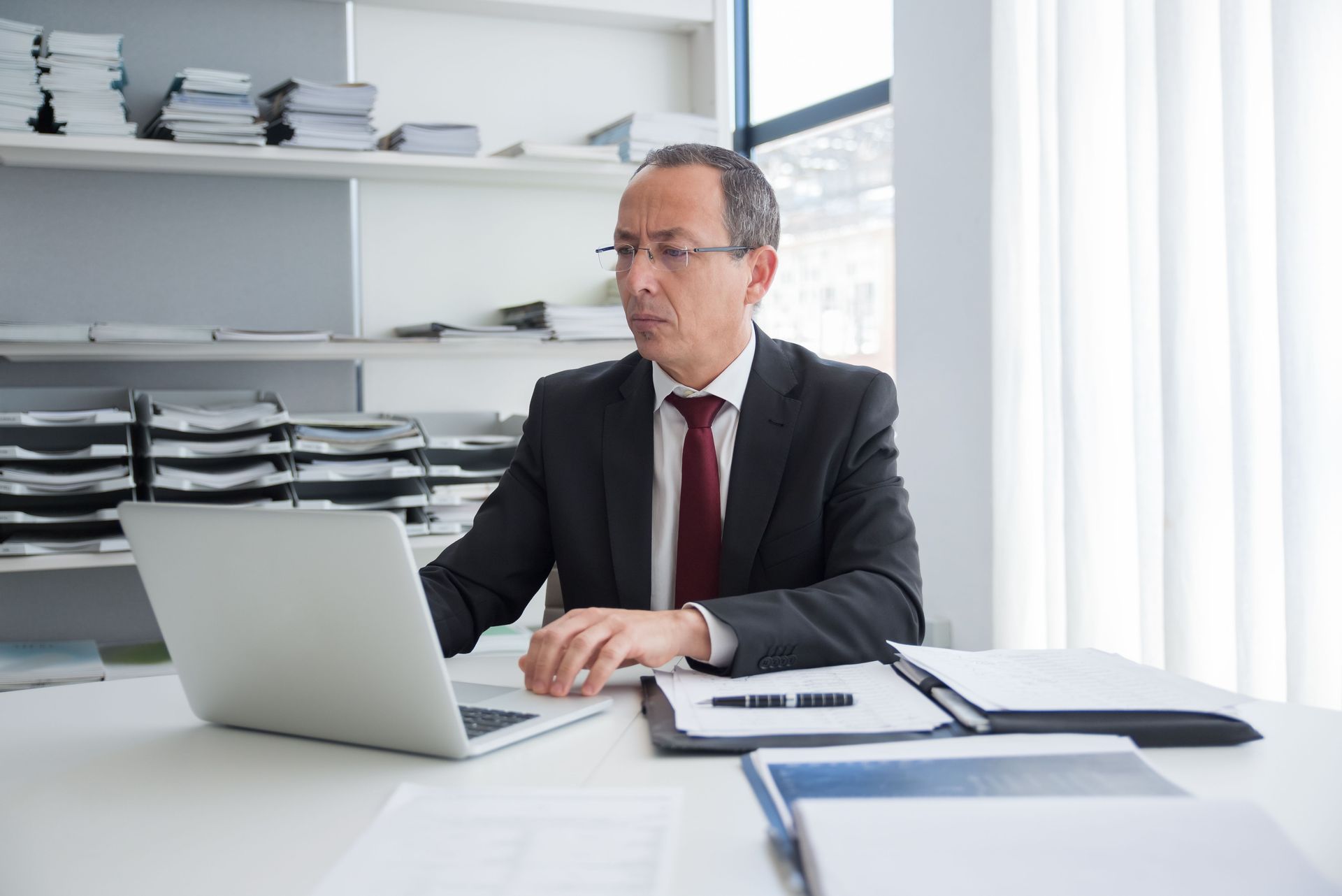 Executive search consultant researching candidates on a laptop at his office desk