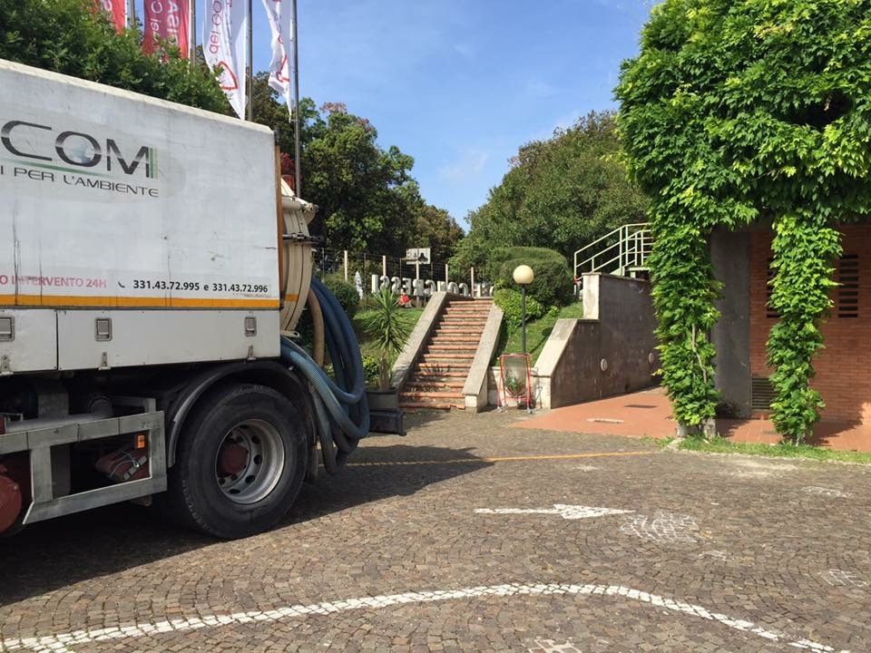Camion parcheggiato accanto a una scalinata alberata e a un muro di mattoni in un vialetto soleggiato