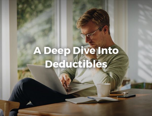 Person studying at a desk with a laptop and notebook, overlaid with the text “A Deep Dive Into Deductibles”