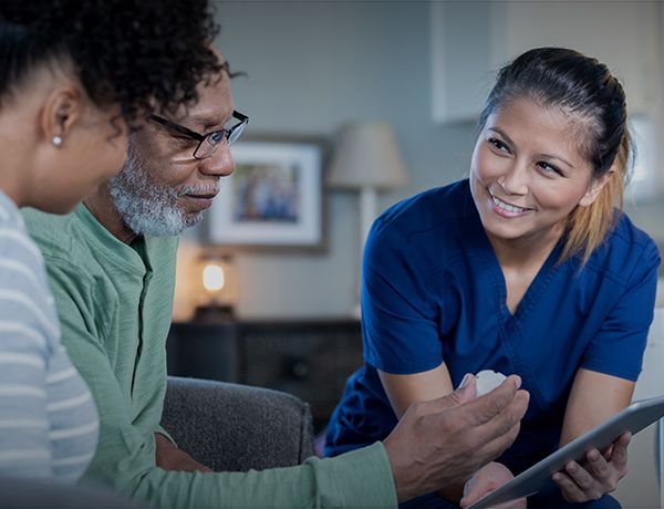 Two people smiling and looking at a tablet in a cozy living room