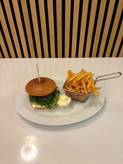 Cheeseburger med salat, tomat og pommes frites på en hvid tallerken