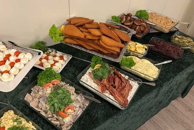 Buffetbord med diverse kager, pålæg, brød og salater arrangeret på fade
