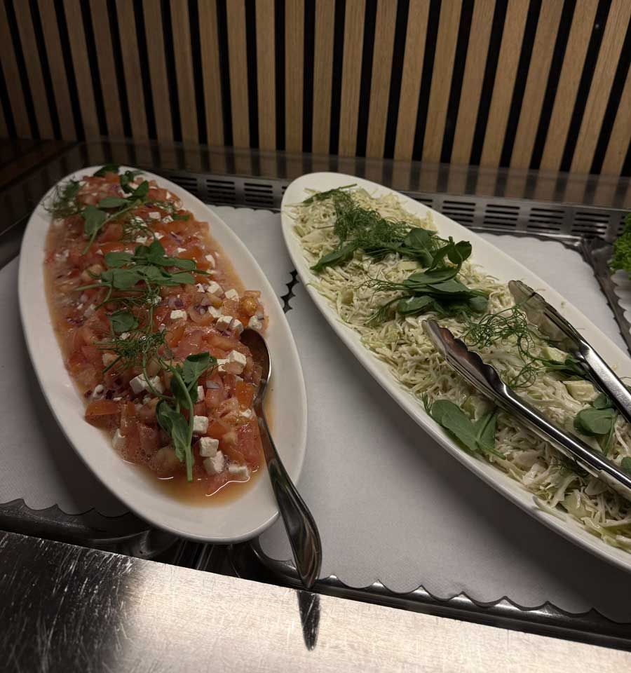 To ovale salatfade: rød tomatblanding til venstre, hvid salat med urter og tang til højre.