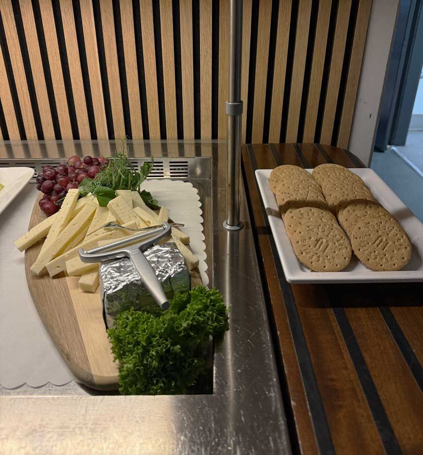 Ostefad med druer og persille ved siden af skiveskåret brød på en buffetdisk