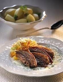 Grillet kød med revne grøntsager på tallerkenen, ved siden af ​​en skål kogte kartofler på et bord