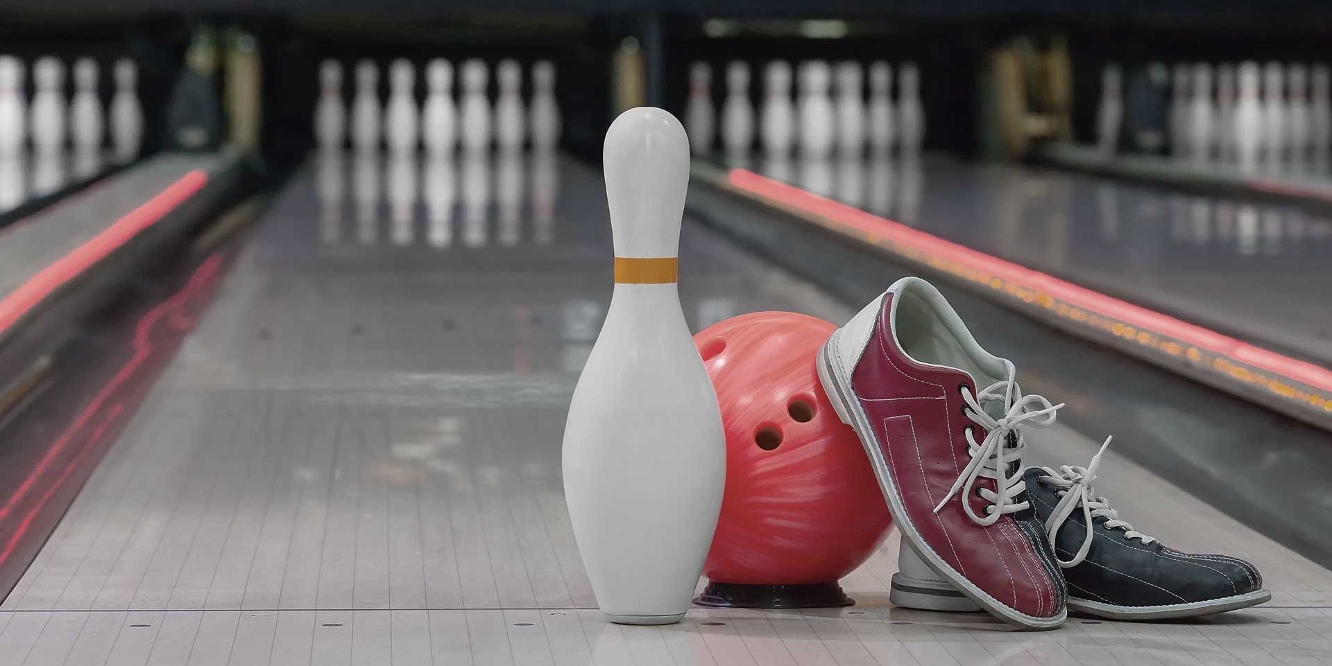 Bowlingbane med en hvid kegle, en rød kugle og to bowlingsko ved siden af
