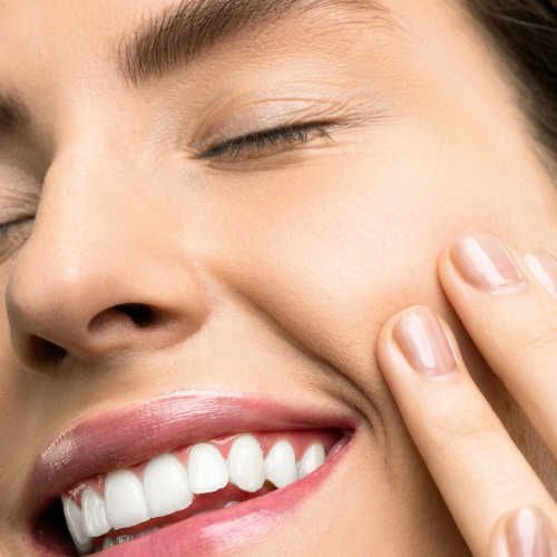 A close up of a woman 's face with her eyes closed and her hand on her face.