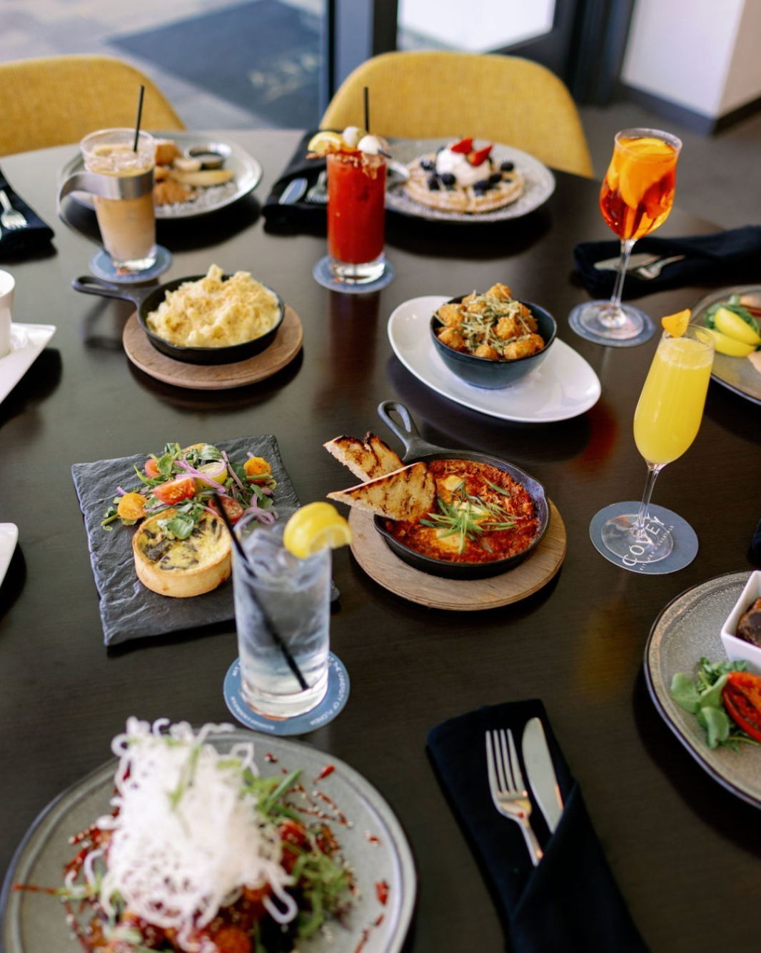 A table of brunch food plates, mimosas and cocktails at Covey Kitchen.